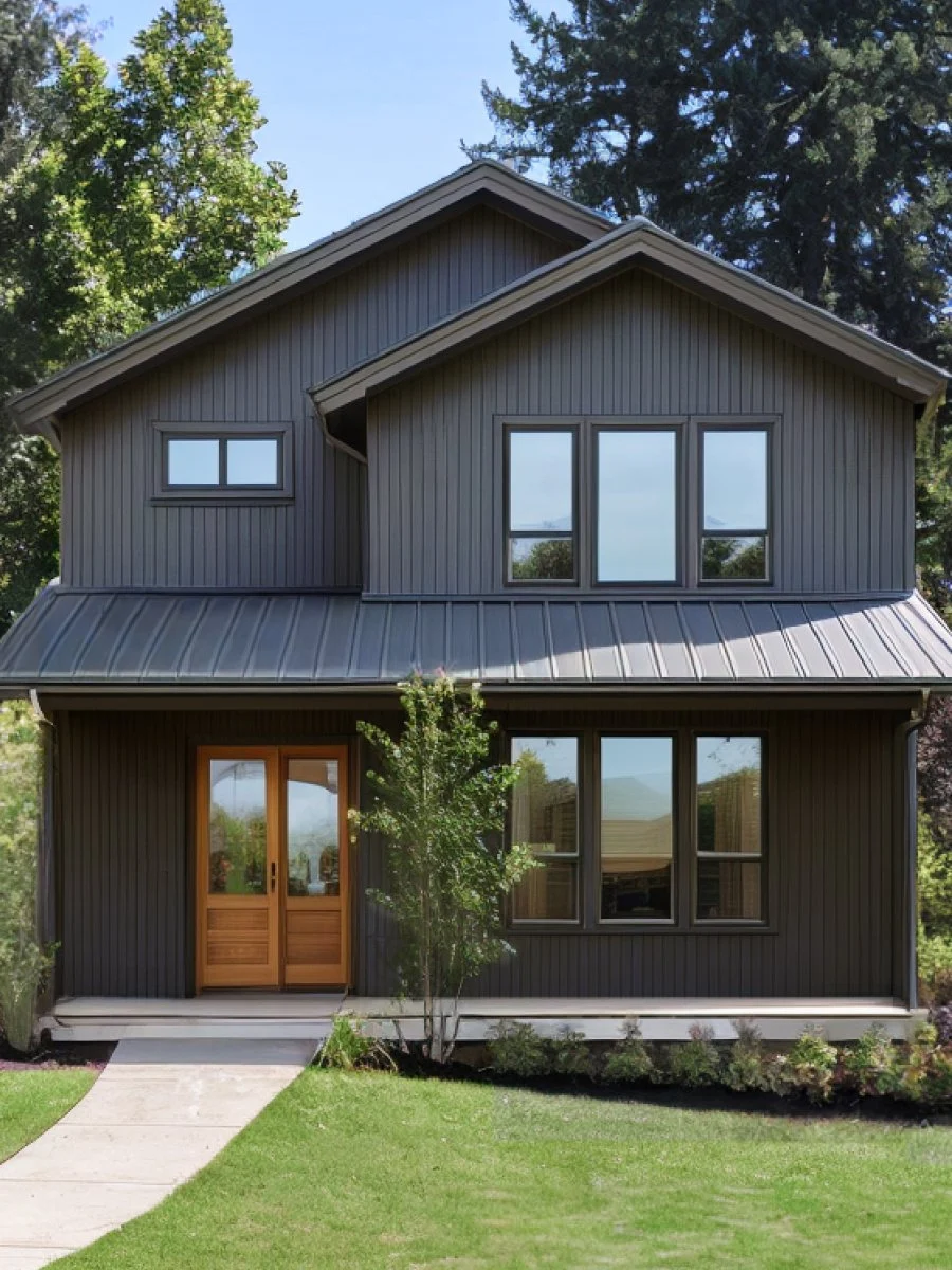 A dark gray house exterior. It’s a two story home with pointed gables and a light brown front door.