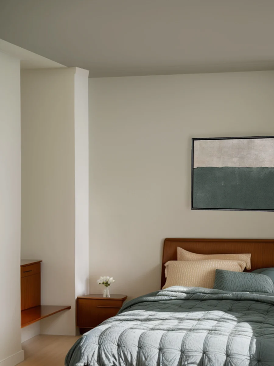 A serene bedroom painted a putty white color. The wooden bed has a light blue coverlet.